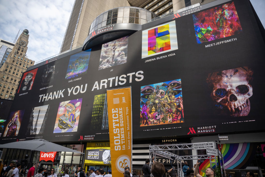 NEW YORK, NEW YORK - JUNE 21: People gather around to watch billboards light up with NFTs as part of the NFT.NYC Conference in Times Square on June 21, 2022 in New York City. Various artists displayed their artwork/ NFTs as part of NFTs minted with NFTKred. (Photo by Alexi Rosenfeld/Getty Images)