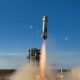 a white rocket launches into a blue sky